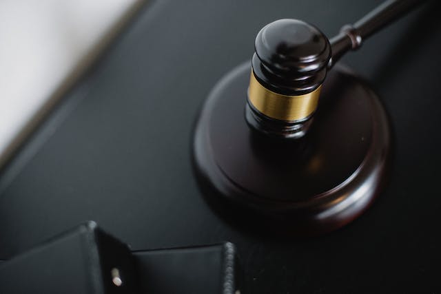 a dark brown and gold judge gavel on a black desk