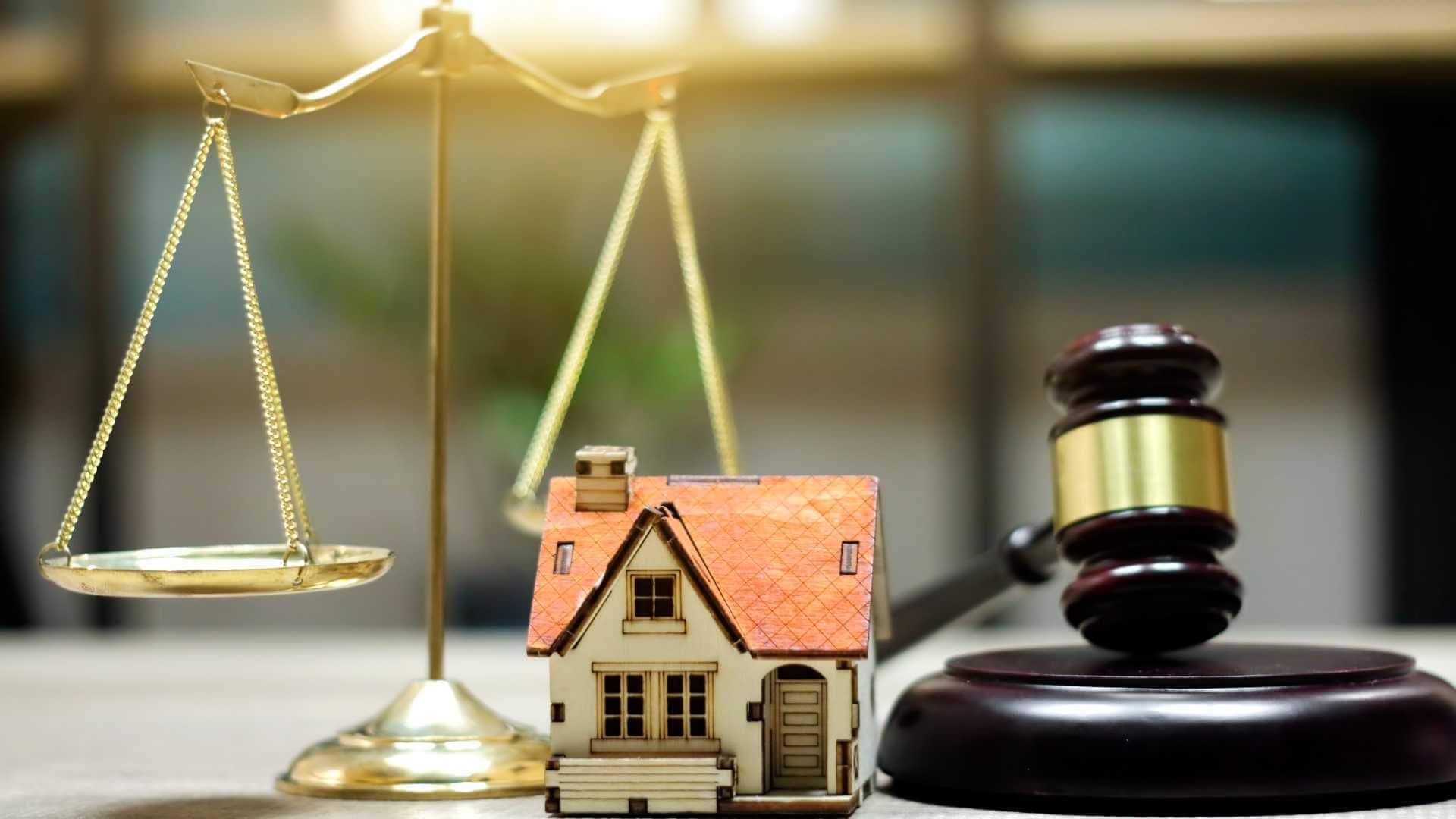 A legal balance, house figurine and judges gavel