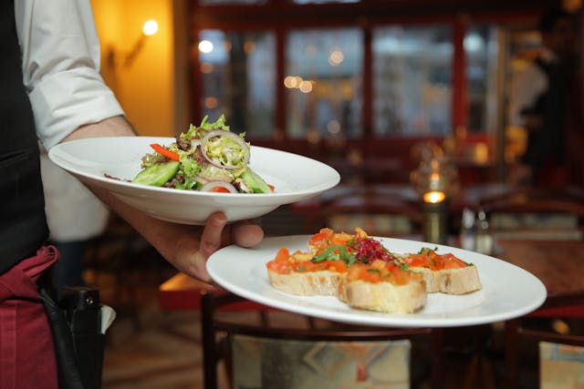 waiter holding salad and bruschetta plates