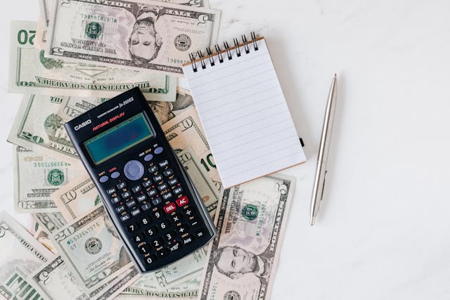 a notepad and calculator on top of money