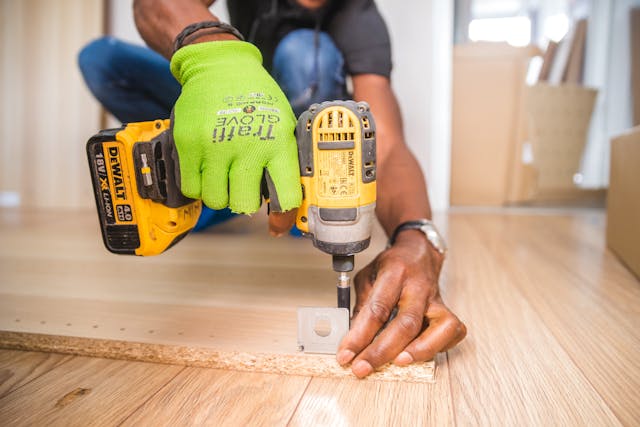 person using a drill while wearing work gloves