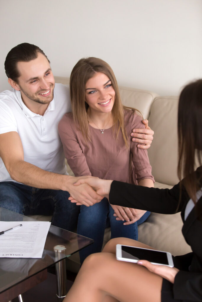 Young married couple talking with a real-estate agent visiting apartment for sale or for rent.