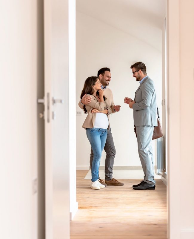 Young,Married,Couple,Talking,With,A,Real-estate,Agent,Visiting,Apartment Young couple signing papers on a property