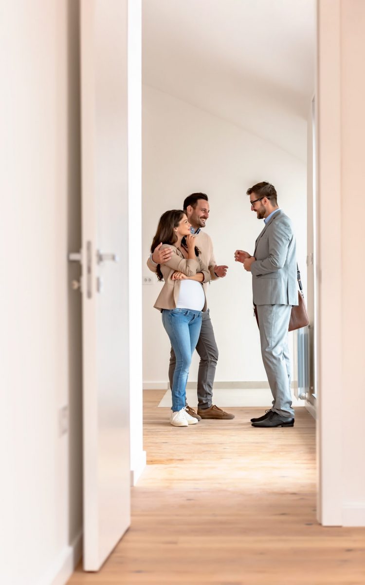 Young,Married,Couple,Talking,With,A,Real-estate,Agent,Visiting,Apartment Young couple signing papers on a property